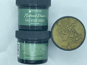 two containers of microgreen powder on top of each other with label facing user. a third container with the lid off it to see what the powder look likes 